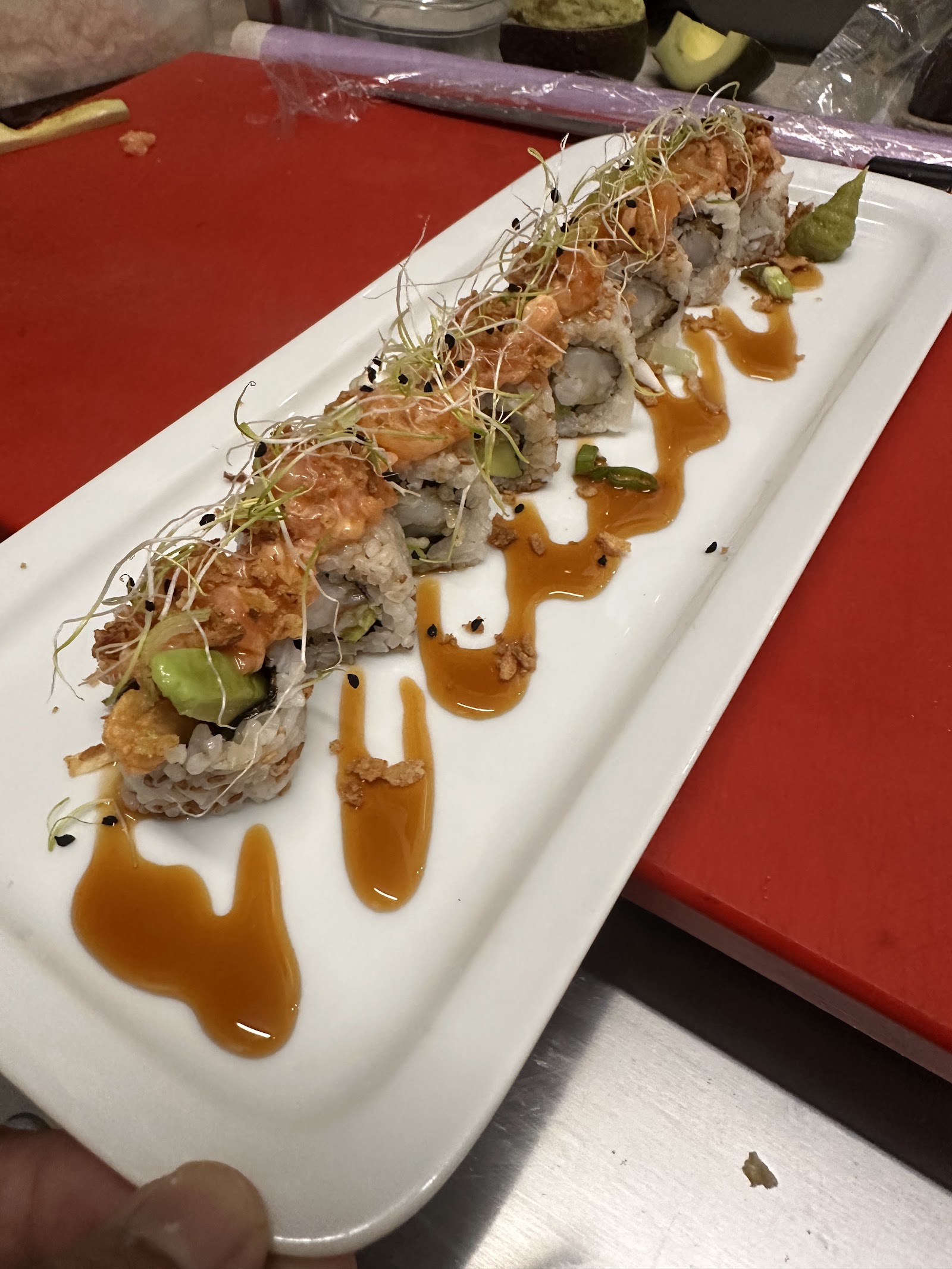 Makis de saumon épicé du Pad Thai Café : riz, avocat, saumon relevé, pousses fraîches, sésame et sauce, dressés sur une assiette blanche.